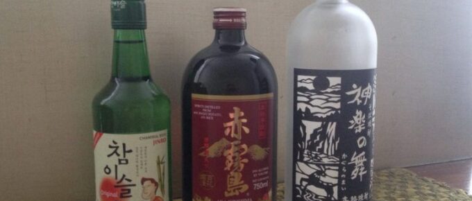 Shochu and soju bottles are lined up on a counter.